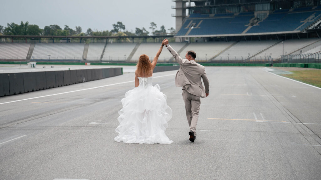 Hockenheimring Hochzeit - Jubelndes Brautpaar auf der Strecke fotografiert von HochzeitUndBild