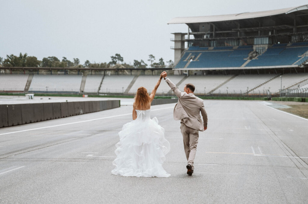 Hochzeit Hockenheimring - BrautpaarShooting Brautpaar laeuft jubelnd auf Rennstrecke