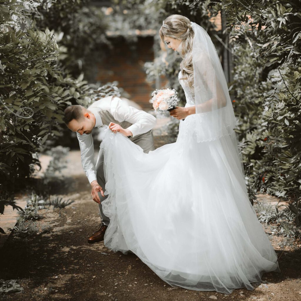 Hochzeitsfotograf Heidelberg_Brautpaarshootign Braeutigam ordnet Brautkleid Q_053