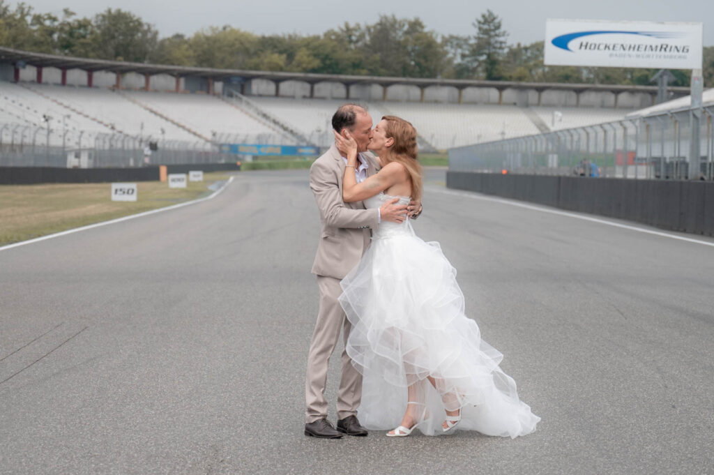 Hochzeitsfotograf Hockenheim - BrautpaarShooting Brautpaar kuesst sich auf Rennstrecke v250604