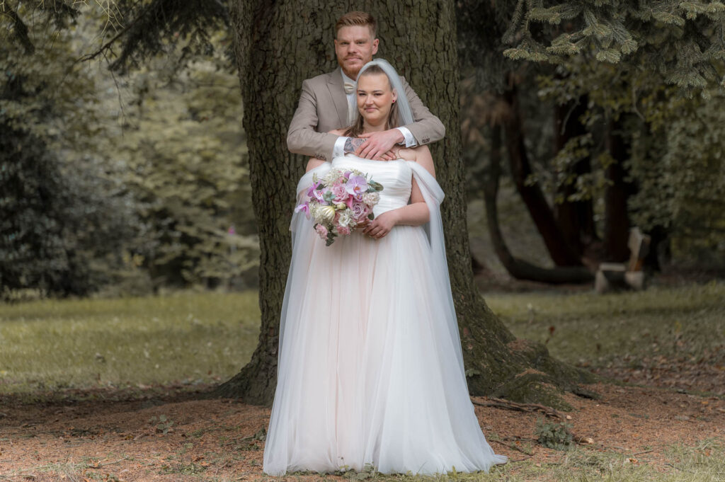 Brautpaarshooting - der Bräutigam steht hinter seiner Braut