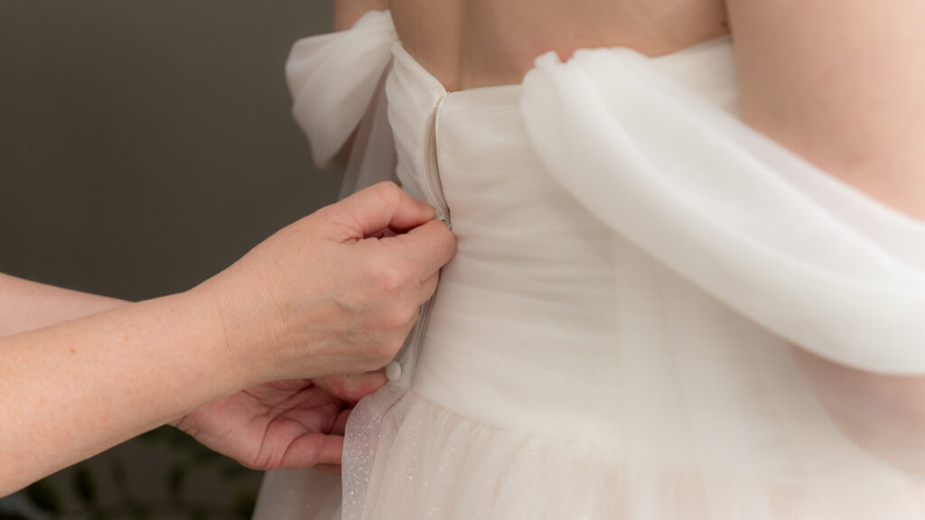 Die Braut hat das Kleid bereits an - es wird nun geschlossen